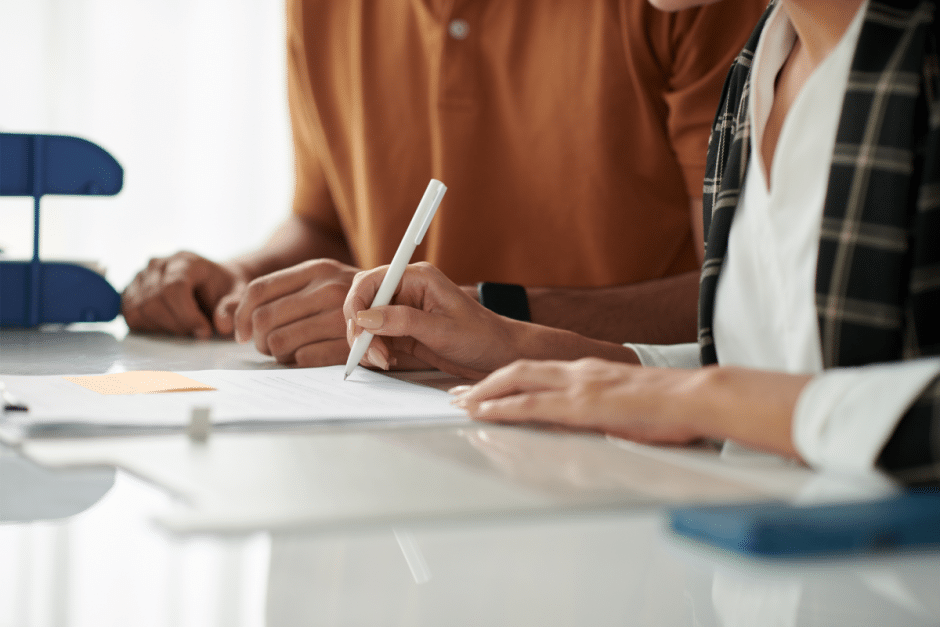 Two people signing paperwork at a desk, symbolising the process of securing landlord insurance.